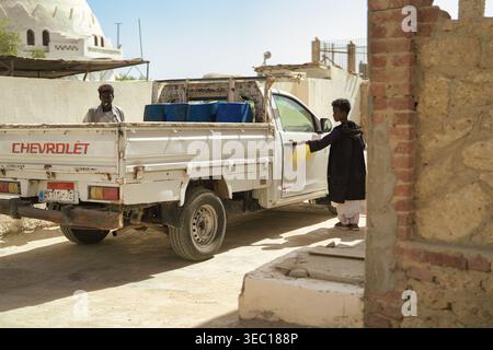 Marsa alam, ägypten 21. april 2026: Junger Mann, der die Tür eines weißen chevrolet-Pickup-Trucks öffnet, während ein anderer Mann hinten steht und blauen barr trägt Stockfoto
