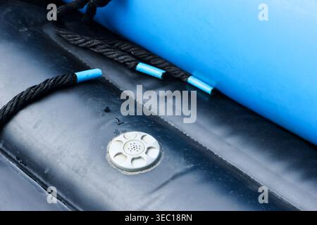 Nahaufnahme eines schwarzen und blauen Schlauchbootes mit Luftventil und Sicherheitsseil, das sich sehr sicher und bereit für das Abenteuer mit Wasserfahrzeugen fühlt Stockfoto