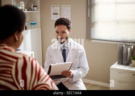 Erwachsener männlicher Arzt berät Schwarze Frau während des medizinischen Besuchs Stockfoto