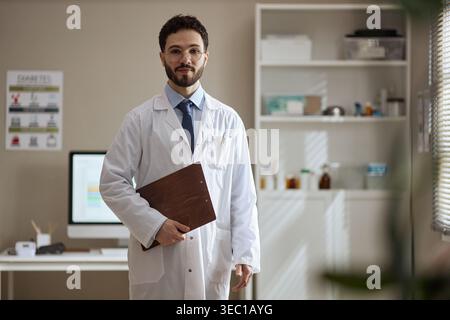 Porträt eines erwachsenen männlichen Arztes, der Clipboard im Klinikbüro hält Stockfoto