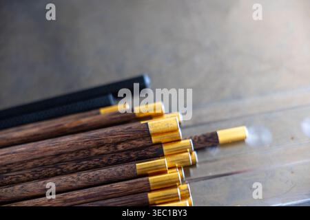 Nahaufnahme von hölzernen Essstäbchen mit Messingende auf grauer Metalloberfläche, die friedliche entspannende ästhetische traditionelle Essensutensilien für asiatische Kuh zeigen Stockfoto