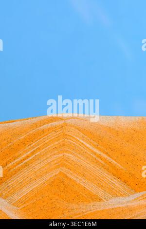 Nahaufnahme der Sandkunst mit strukturierten Berggipfeln vor leuchtend blauem Hintergrund Stockfoto