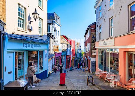 Die Old High Street ist eine steile und enge Kopfsteinpflasterstraße, die von farbenfrohen Geschäften im Creative Quarter von Folkestone, Kent, England, gesäumt wird Stockfoto