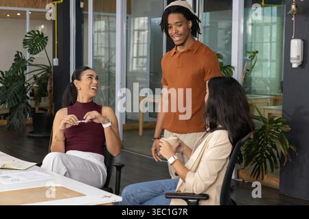 Verschiedene Kollegen in Business- und Freizeitkleidung diskutieren am weißen Tisch mit einem Papierbecher-Desinfektionsmittel Stockfoto