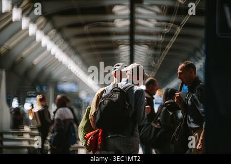 Zürich, Schweiz, 23. April 2026. Eine Gruppe Männer steht auf einem Bahnsteig in Zürich HB, einer isst ein Eis, unter dem charakteristischen Gewölbe-gl Stockfoto