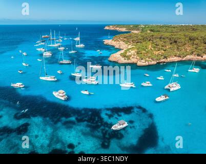 Blick aus der Vogelperspektive auf Luxusyachten und Boote, die im türkisfarbenen Meer vor Anker liegen Stockfoto