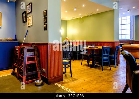 London UK, 28. April 2026, Frau, die allein in einem Coffee Shop sitzt und ein heißes Getränk genießt Stockfoto