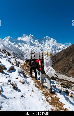 Sherpa-Träger tragen Trekkingausrüstung zwischen Thukla und Pheriche, Himalaya, Nepal Stockfoto
