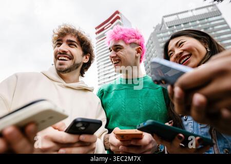 Verschiedene junge Freunde, die Spaß mit Mobiltelefonen auf der Stadtstraße haben Stockfoto