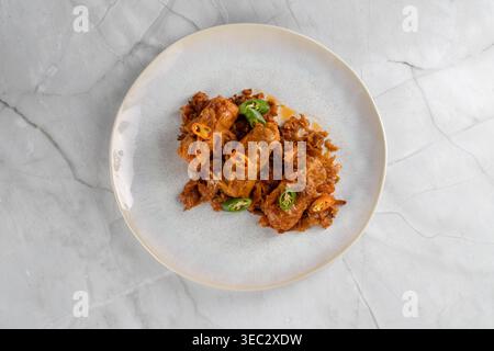 Flaches Lagen traditioneller Kohlbrötchen auf gehacktem Kohl, dekoriert mit geschnittenen Chili-Paprika auf einem runden Teller auf hellem Marmorhintergrund. Stockfoto