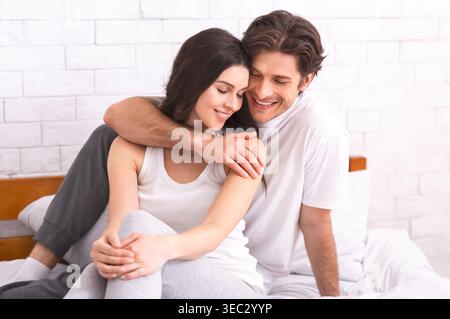 Paare teilen einen freudigen Moment gemeinsam in einem gemütlichen Schlafzimmer im sanften Morgenlicht Stockfoto