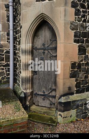 Gotische hölzerne Kirchentür in alter verwitterter Steinmauer Stockfoto