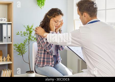 Arzt hört Patienten mit Kopfschmerzen in der Klinik zu und bietet Beratung an. Stockfoto