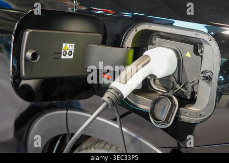 Nahaufnahme des Ladeanschlusses für Elektrofahrzeuge mit eingestecktem Ladeanschluss bei modernen schwarzen Elektrofahrzeugen Stockfoto