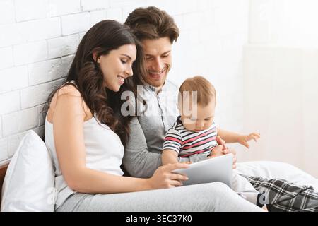 Die Familie genießt eine gute gemeinsame Zeit, während sie mit einem Tablet in einem hellen Raum spielt Stockfoto