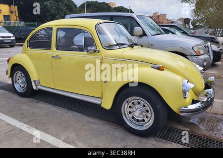 Ein klassischer, hellgelber Volkswagen-Käfer mit individuellen Chrommodifikationen und Scheinwerferblenden, der auf einer Straße in Andalusien geparkt ist. Stockfoto