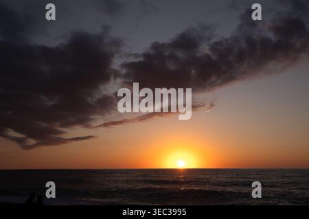 Goldene Sonne untergeht über dem Ozeanhorizont mit dunklen dramatischen Wolken Stockfoto