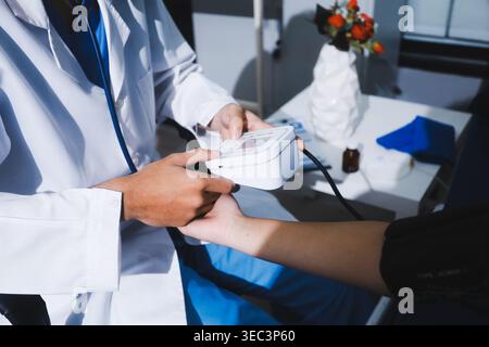 Arzt im Krankenhaus mit manuellem Blutdruckmessgerät zur Messung des Blutdrucks und Pulses von Patientinnen. Stockfoto
