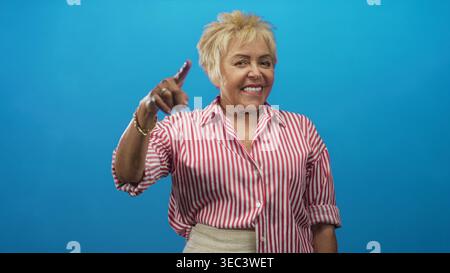 Die ranghöchste hispanische Frau berührt den Tempel und zeigt den Finger im Studio mit sichtbarer Handbewegung nach außen; warmes Selbstvertrauen. Stockfoto