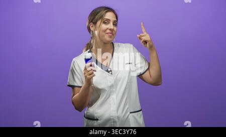 Krankenschwester hält Arzneimittelflasche und zeigt den Zeigefinger im Studio nach oben; selbstbewusste Fürsorgeführung. Stockfoto