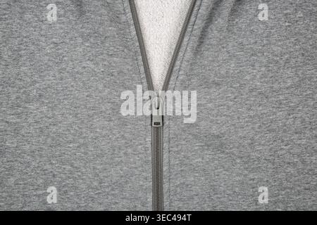 Nahaufnahme eines halboffenen Metallreißverschlusses auf grauem meliertem Hoodie-Material. Stockfoto