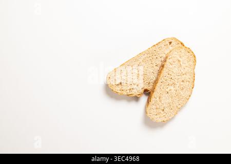 Zwei frische Vollkornbrotscheiben auf weißem Hintergrund, rustikale goldene Kruste und strukturierte Krume, gesunde Quelle von Ballaststoffen und komplexe Kohlenhydrate für die Gesundheit Stockfoto