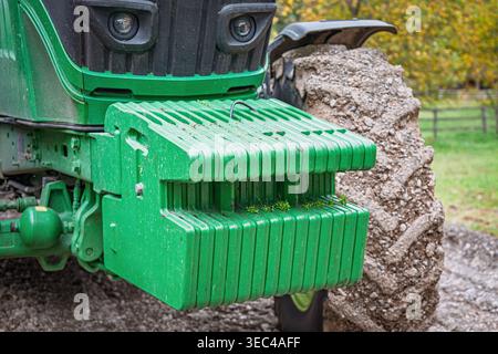 Umweltfreundlicher Traktor mit Frontgewichten, das schwere Anbaugerät hinten ausbalanciert und Landmaschinen in Aktion zeigt Stockfoto