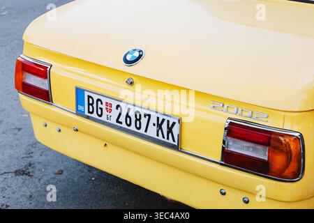 25. Oktober 2025, Belgrad, Serbien: Rückansicht eines klassischen gelben BMW 2002-Automobils mit Kofferraum, Emblem, Lichtern und serbischem Kennzeichen Stockfoto