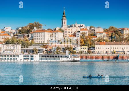 25. Oktober 2025, Belgrad, Serbien: Skyline der Stadt von der Save mit historischen Gebäuden, einem markanten Kirchturm und einem großen Kreuzfahrtschiff d Stockfoto