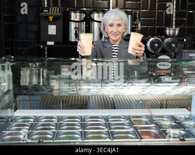 Lächelnde Senior Verkäuferin, die erfrischenden taiwanesischen boba-Tee anbietet Stockfoto