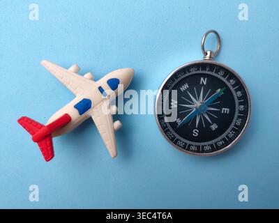 Das Bild zeigt ein Spielzeugflugzeug und einen magnetischen Kompass, die wahrscheinlich ein Reise- oder Abenteuermotiv symbolisieren. Stockfoto