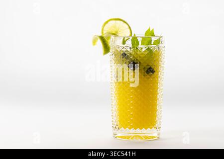 Erfrischendes Zitrusgetränk mit Orangensaft, Limettenscheiben, Heidelbeeren und frischen grünen Minzblättern, serviert in strukturiertem Glas, isoliert auf weißem Hintergrund Stockfoto