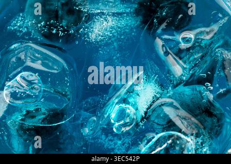 Eine hellblaue Flüssigkeit mit Eis und Heidelbeeren, die eine abstrakte Textur schafft, die erfrischende und coole Konzepte hervorruft. Stockfoto