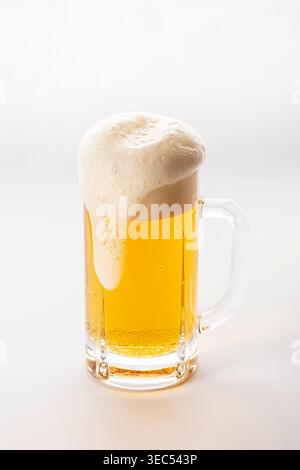 Studio-Aufnahme eines goldenen Bieres in einem Glasbecher mit dickem, cremigem Schaum, isoliert auf einem sauberen weißen Hintergrund. Erfrischungskonzept, Getränk Stockfoto