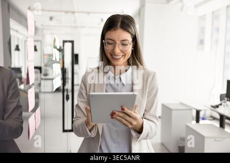 Junge professionelle Frau aus den 30er Jahren, die ein digitales Tablet verwendet Stockfoto