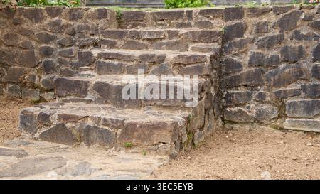 Rau dunkle Steintreppen, die in die Felswand eingebaut sind, Gartentreppe, die zum Rasen führt, Seitenansicht mit Kopierraum, Landschaftsgestaltung und Gartengestaltung Stockfoto