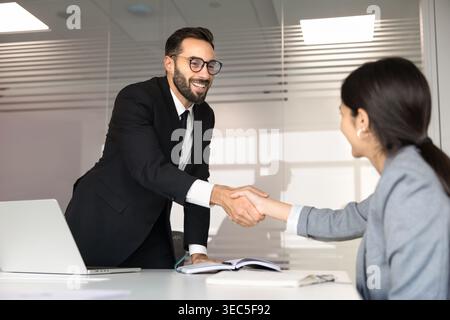 Ein lächelnder hispanischer Geschäftsmann schüttelt der Kundin oder Kollegin die Hand Stockfoto
