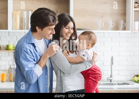 Happy Family genießt die gemeinsame Zeit in einer modernen Küche, während sie mit ihrem Baby spielt Stockfoto