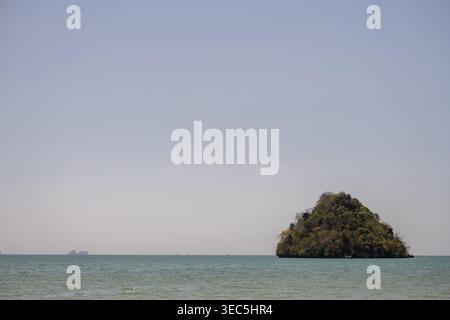 Kleine Kalksteininsel erhebt sich aus ruhigem tropischem Meer unter klarem Himmel in Krabi Thailand Stockfoto