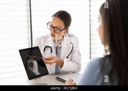 Der Arzt zeigt dem Patienten die Ergebnisse des Röntgen-Scans auf einem digitalen Tablet Stockfoto