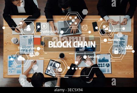Eine Top-down-Ansicht eines professionellen Geschäftsmeetings mit Schwerpunkt auf Blockchain-Technologie, bei dem Teammitglieder mit Laptops und detaillierten Daten konfrontiert werden Stockfoto
