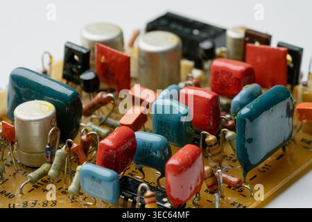 Nahaufnahme einer Vintage-Leiterplatte mit verschiedenen bunten Widerständen und Kondensatoren. Retro-elektronische Hardwarearchitektur. Detaillierte interne Ansicht von Stockfoto