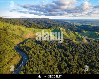 Der New Zealand State Highway 29 verläuft entlang der Kaimai Range. Auf der einen Seite der Straße befindet sich Ackerland, auf der anderen Seite dichter einheimischer Wald Stockfoto