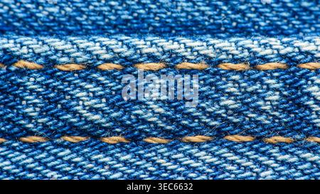 Blauer Denim in Nahaufnahme mit gewebter Textur und orangefarbenen Nähten. Robustes Baumwollmaterial für Jeans, Polster und Mode. Thailand Fotografie, Stockfoto