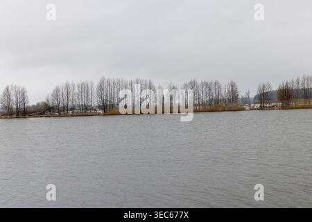 Ein Fluss im frühen Frühjahr nach Schneefällen und Winterfrösten ist das Eis auf dem Fluss geschmolzen, grau bewölkter Frühlingshimmel bevor es sich erwärmt, schmilzt das Eis Stockfoto