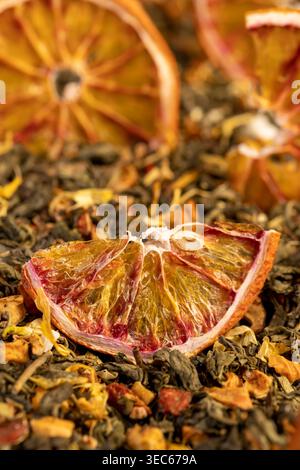 Tee mit hinzugefügten Fruchtstücken und geschnittenen getrockneten roten Orangen, helle große trockene Scheiben blutroter Orange und grüner Tee mit Fruchtstücken, Nahaufnahme Stockfoto