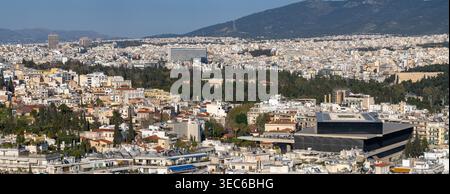 Erhöhter Blick auf das moderne Akropolis-Museum im Vordergrund mit der weitläufigen Stadtlandschaft von Athen, die sich bis zu den Bergen erstreckt. Stockfoto