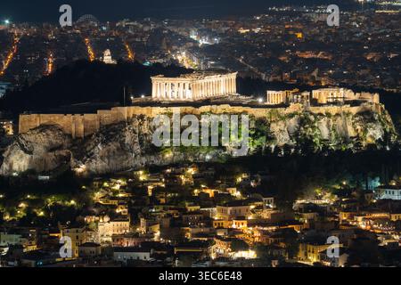 Beleuchtete Akropolis und Plaka-Viertel bei Nacht in Athen. Stockfoto