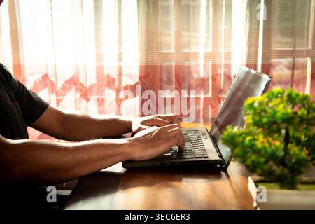 Nahaufnahme von männlichen Händen, die auf der Laptop-Tastatur im Home Workspace tippen Stockfoto