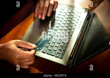 Großer Winkel des Mannes, der die Kreditkarte hält und auf dem Laptop schreibt Stockfoto
